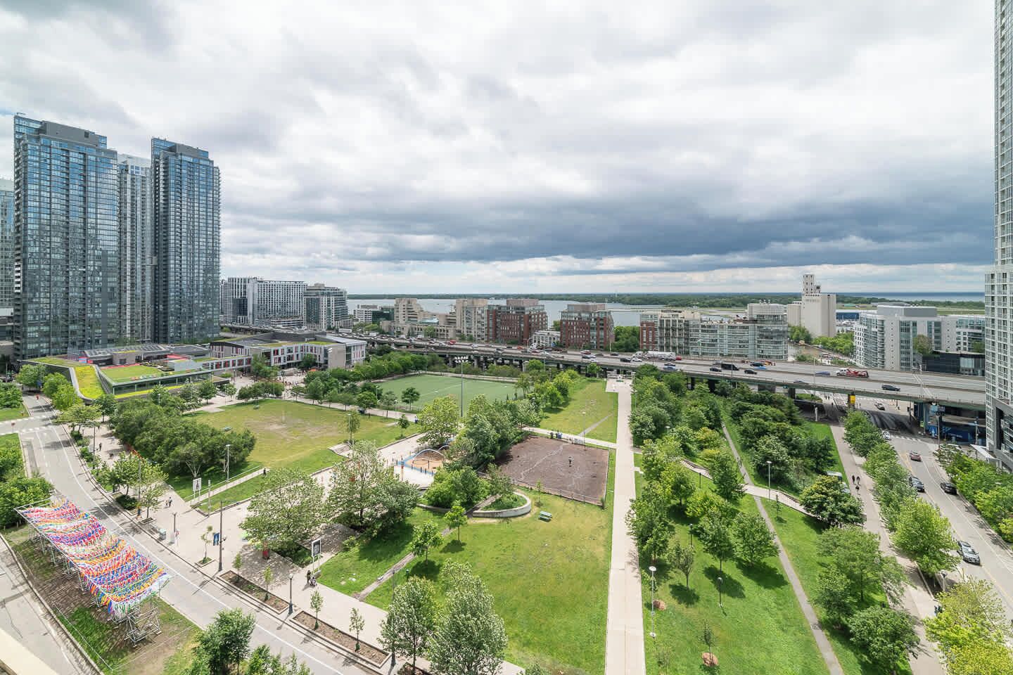 Stadsbeeld met moderne wolkenkrabbers, een centraal park met een sportveld, en een brug die twee gebieden verbindt.