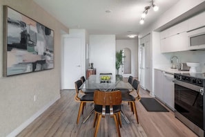 A modern kitchen with a built-in oven, a microwave, and a dining area with a glass table and chairs. - Chic 2BR Downtown King Suite Parking Sleeps 6 | Parking Available (Toronto)