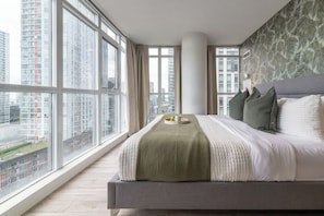 Una camera d'albergo moderna con un letto grande, vista sulla città e una finestra con tende.