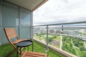 A balcony with a view of a cityscape, a wooden chair, and a small table. - Chic 2BR Downtown King Suite Parking Sleeps 6 | Parking Available (Toronto)