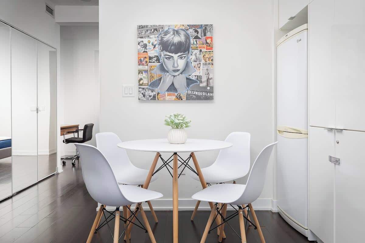 A modern dining area with a white table, four white chairs, and a central plant.