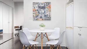 A modern dining area with a white table, four white chairs, and a central plant. - Downtown Escape Stylish Condo with City Views (Toronto)