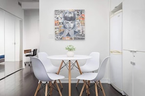 A modern dining area with a white table, four white chairs, and a central plant.