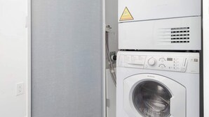 A front-loading washing machine with a control panel, a detergent bottle, and a box on top.
