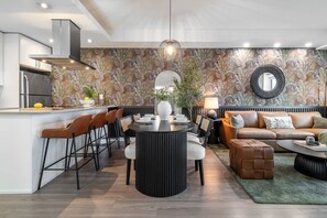 A modern kitchen with a central island, dining area with chairs, a sofa, and a coffee table.