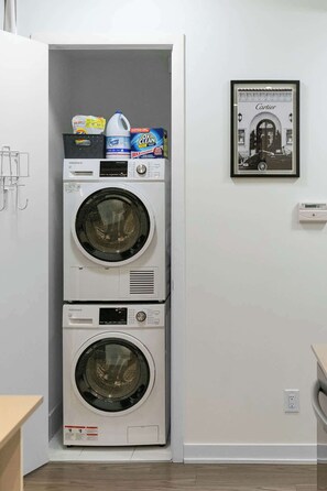 Een gestapelde wasmachine en droger, met wasmiddeldozen erbovenop.