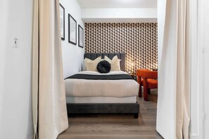 Een slaapkamer met een bed, een stoel en een behang met een patroon.
