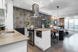 A modern kitchen with a central island, a dining area with a round table, and a large window offering a view.