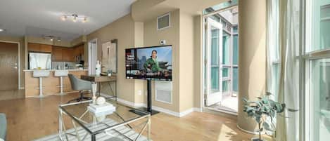 A modern living room with a flat-screen TV, a glass coffee table, and a sofa.