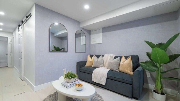 Un salon moderne avec un canapé gris, une table basse et une grande plante.