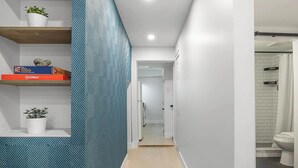 Un couloir avec un mur orné de motifs, une boîte de Scrabble et une plante en pot.