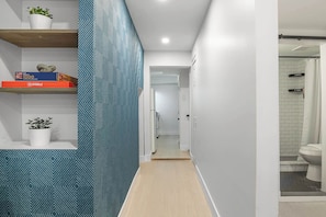 A hallway with a patterned wall, a Scrabble box, and a potted plant. - Modern Basement Suite Heart of Ossington (Toronto)