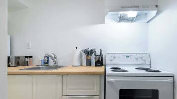 A kitchen with a white stove, a sink, and a countertop with various kitchen items.