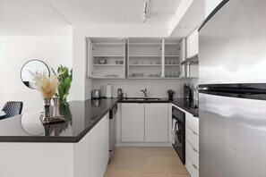 Una cocina moderna con armarios blancos, una encimera negra y un horno integrado.
