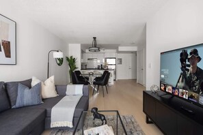 Ein modernes Wohnzimmer mit einer Couch, einem Couchtisch und einem Fernseher, der einen Film zeigt.
