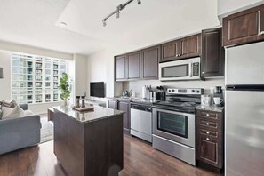 A modern kitchen with a central island, stainless steel appliances, and dark wood cabinetry. - Urban Harbor Haven Modern 1BR Living Downtown | Parking Available (Toronto)