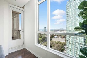 A room with a large window, a door, and a view of a cityscape. - Urban Harbor Haven Modern 1BR Living Downtown | Parking Available (Toronto)