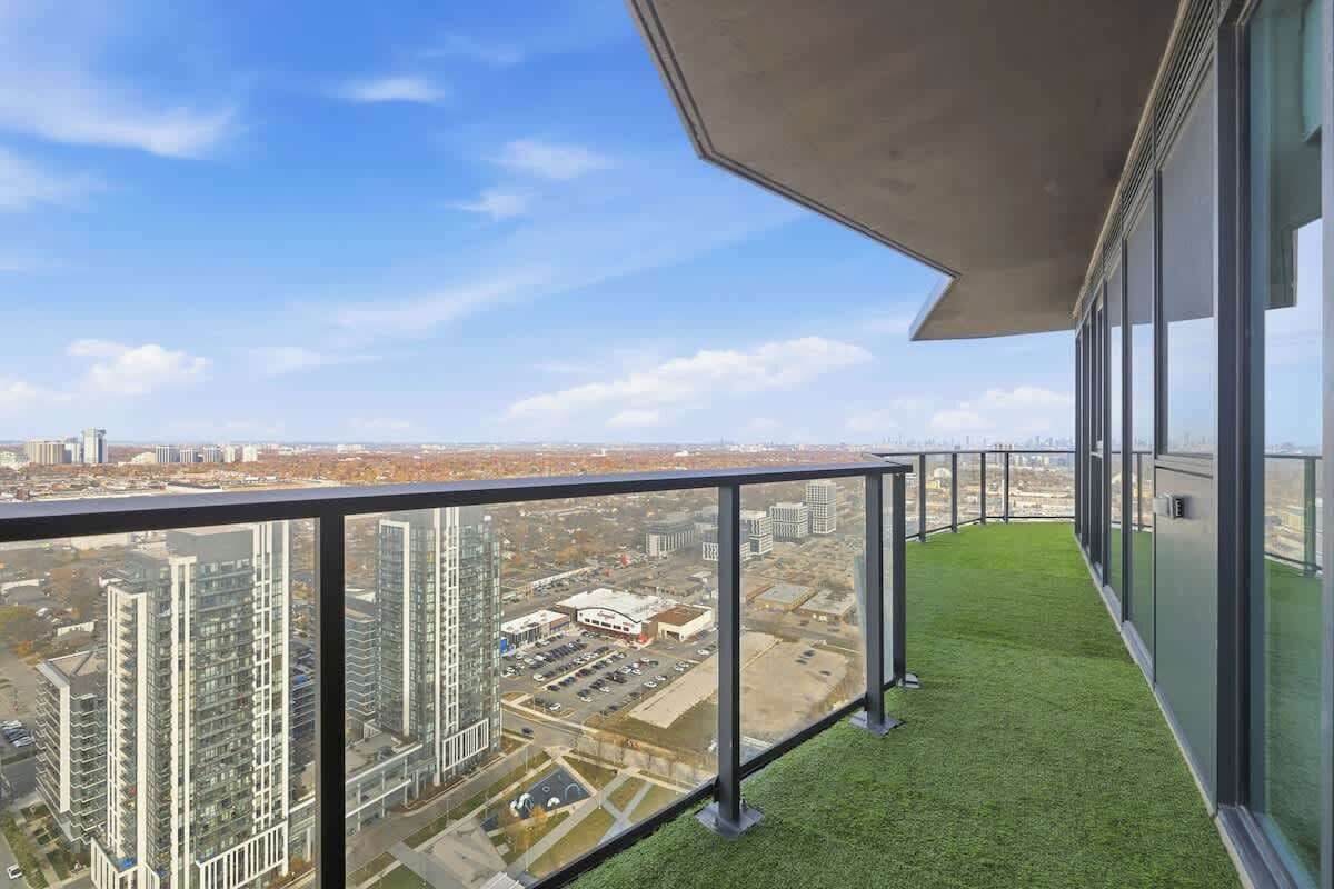 Ein Balkon mit freiem Blick auf die Stadt, darunter hochliegende Gebäude und ein Parkplatz.