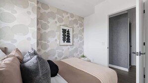 A modern bedroom with a bed, pillows, a bedside table, and a wall with a circular pattern.