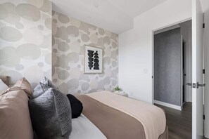 Une chambre à coucher moderne avec un lit, des oreillers, une table de chevet et un mur orné d’un motif circulaire.