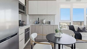A modern kitchen with a built-in microwave, a dining area with a round table, and a view of the outdoors through large windows.