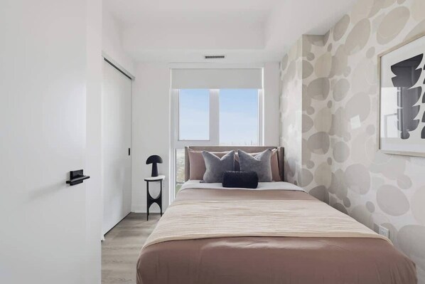 A bedroom with a bed, a window, and a door.