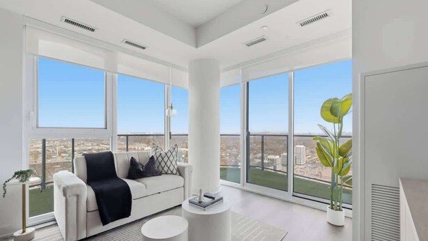 A modern living room with a sofa, coffee table, and large windows offering a city view.