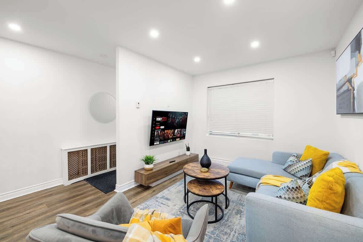 A modern living room with a flat-screen TV, a sofa set, a coffee table, and a decorative vase.