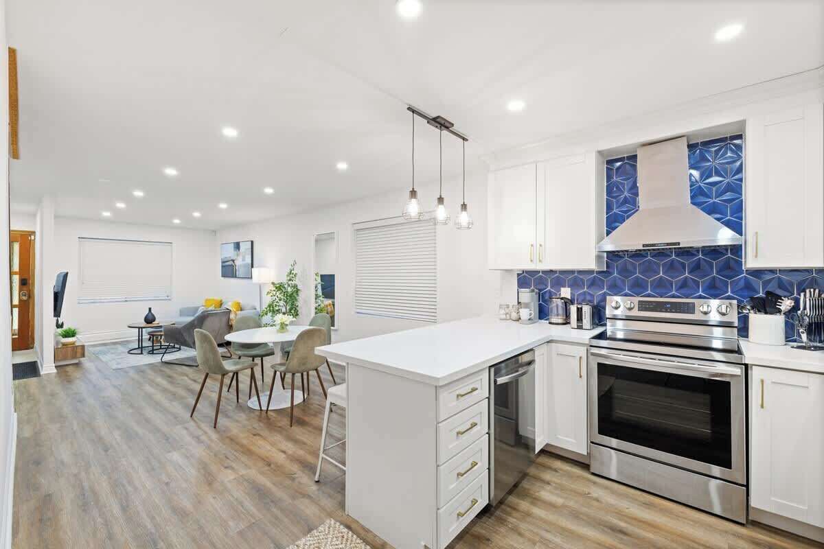 A modern kitchen with white cabinetry, a built-in oven, and a blue backsplash.