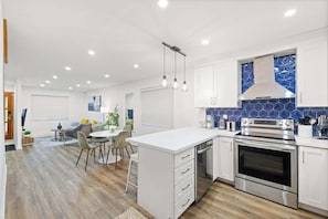 A modern kitchen with white cabinetry, a built-in oven, and a blue backsplash.
