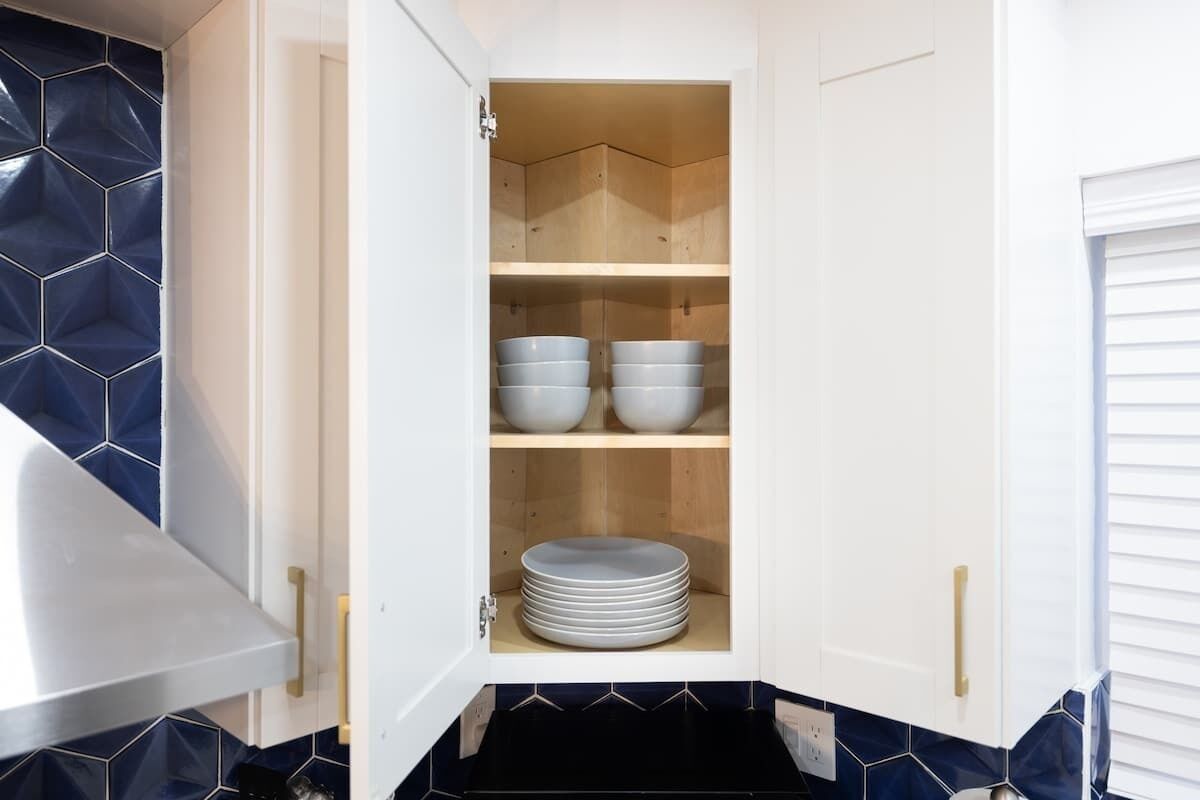 A kitchen cabinet with multiple shelves, some containing plates and bowls.