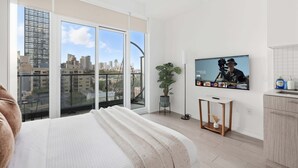 Um apartamento moderno com uma varanda ampla, uma televisão fixada na parede e uma cozinha minimalista.
