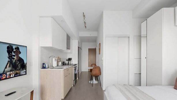 Quarto de hotel moderno e compacto, com cozinha compacta, área de jantar e quarto separado.