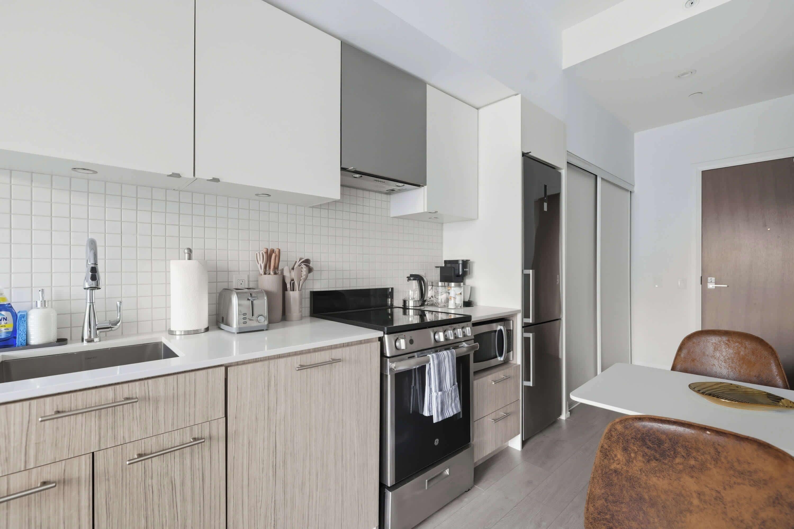 A modern kitchen with a stainless steel stove, a sink, and a dining area with a table and chairs.
