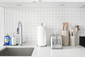 A modern kitchen with a stainless steel sink, a toaster, and a container holding kitchen utensils. - Coffee Mornings & City Skylines, Toronto Studio! (Toronto)