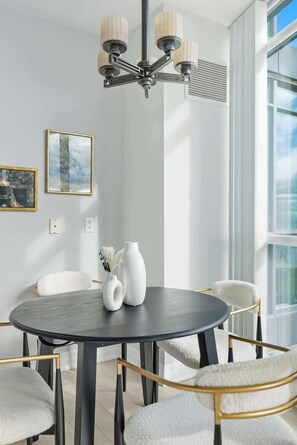 A modern dining area with a round table, white chairs, and a chandelier. - Luxury 2BR Condo with King Beds & Views (Toronto)