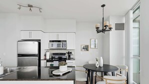 Une cuisine moderne dotée d’un îlot central, d’appareils électroménagers en acier inoxydable et d’un coin repas avec une table ronde et des chaises.