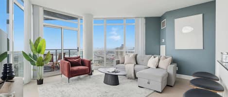 A modern living room with a large window, a red armchair, a grey sofa, and a coffee table.