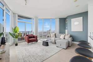 A modern living room with a large window, a red armchair, a grey sofa, and a coffee table. - Luxury 2BR Condo with King Beds & Views (Toronto)