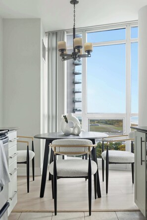 A modern kitchen with a dining table, chairs, and a chandelier.
