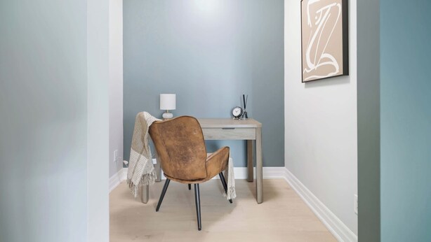 Une pièce comprenant un bureau, une chaise, une lampe et une œuvre d’art encadrée accrochée au mur.