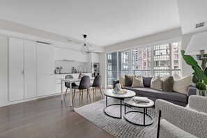 A modern living room with a sofa, two chairs, a coffee table, and a dining area with a table and chairs. - Financial District 2BR Condo, 55" TV, Free Parking (Toronto)