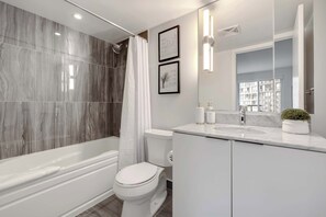Une salle de bain moderne équipée d’une baignoire, de toilettes et d’un meuble-lavabo avec un miroir.
