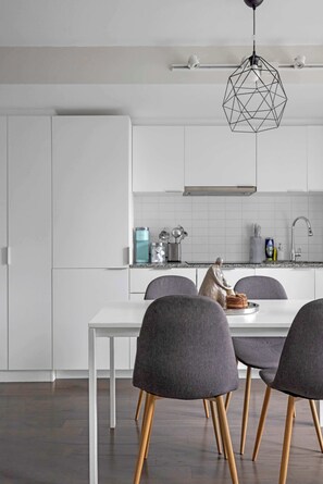A modern kitchen with white cabinetry, a dining table with four chairs, and a geometric pendant light. - Financial District 2BR Condo, 55" TV, Free Parking (Toronto)