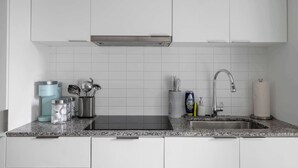 Ett modernt kök med vita skåp, en diskho i rostfritt stål och en bänkskiva i granit.