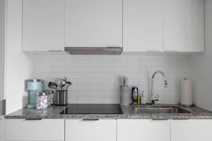 Eine moderne Küche mit weißen Schränken, einer Edelstahl-Spüle und einer Arbeitsplatte aus Granit.