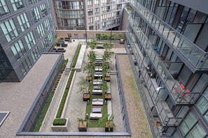 Une terrasse sur le toit, aménagée avec des espaces pour s’asseoir, des jardinières et offrant une vue dégagée sur les bâtiments environnants.