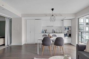 Una cocina moderna con armarios blancos, una mesa de comedor con sillas y un horno empotrado.