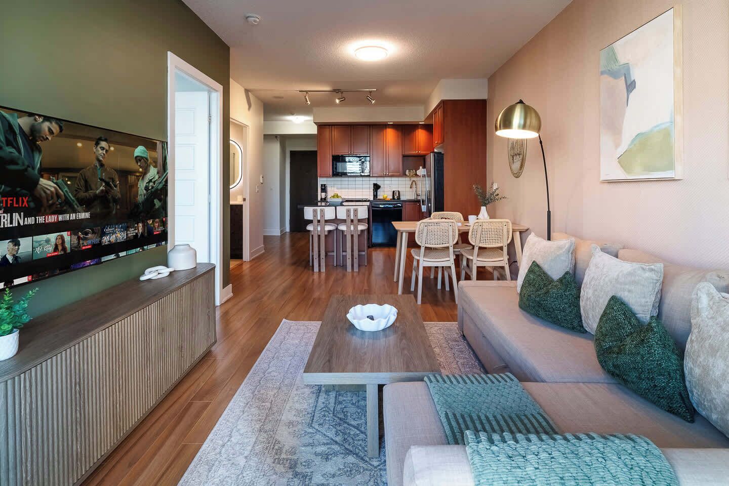 Un salon moderne avec un téléviseur à écran plat, un canapé, une table basse et un coin repas avec des chaises.