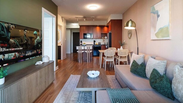 Un salon moderne avec un téléviseur à écran plat, un canapé, une table basse et un coin repas avec des chaises.